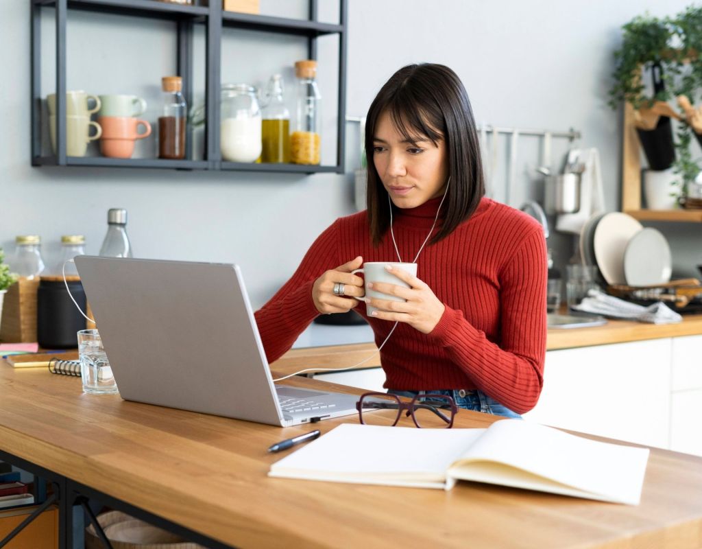 Frau im Home Office vor dem Laptop mit Teetasse