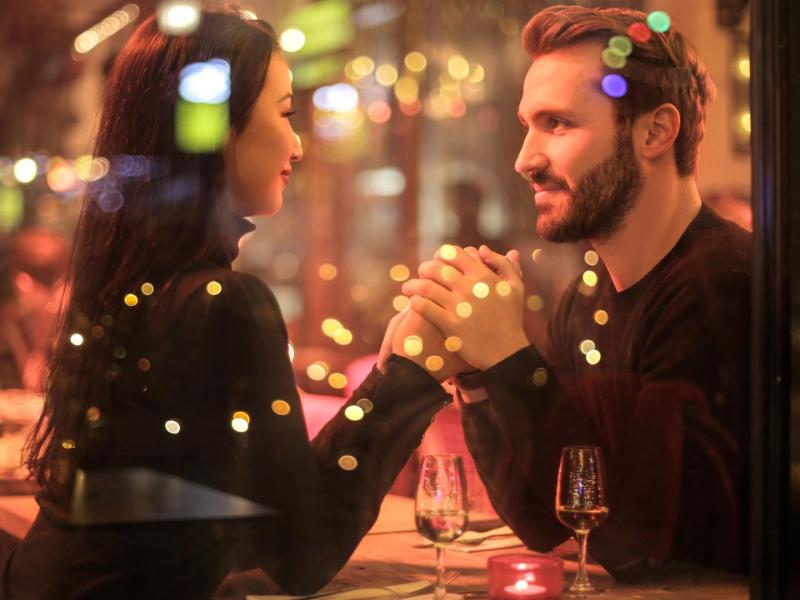 Ein Pärchen sitzt in einem Restaurant bei einem  Date hält Händchne