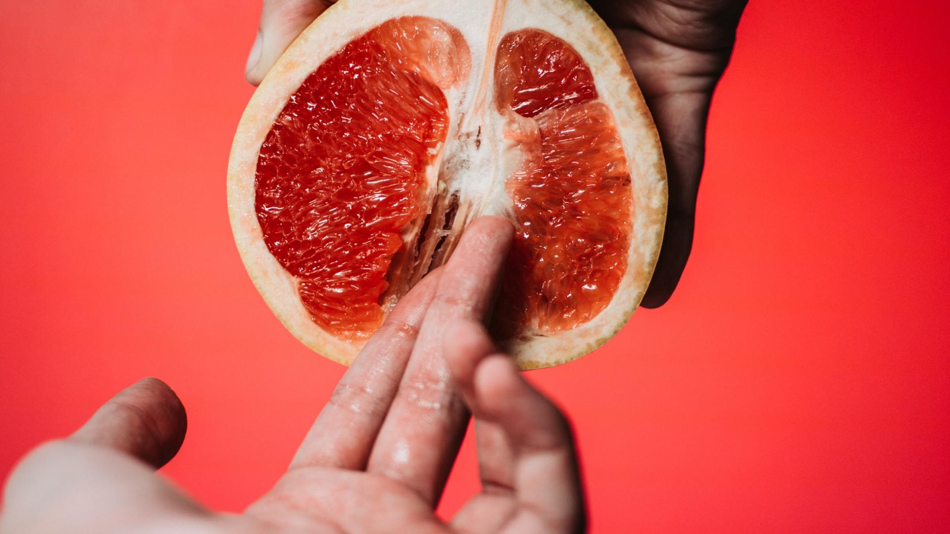 zwei Finger in der Mitte einer saftigen Grapefruit