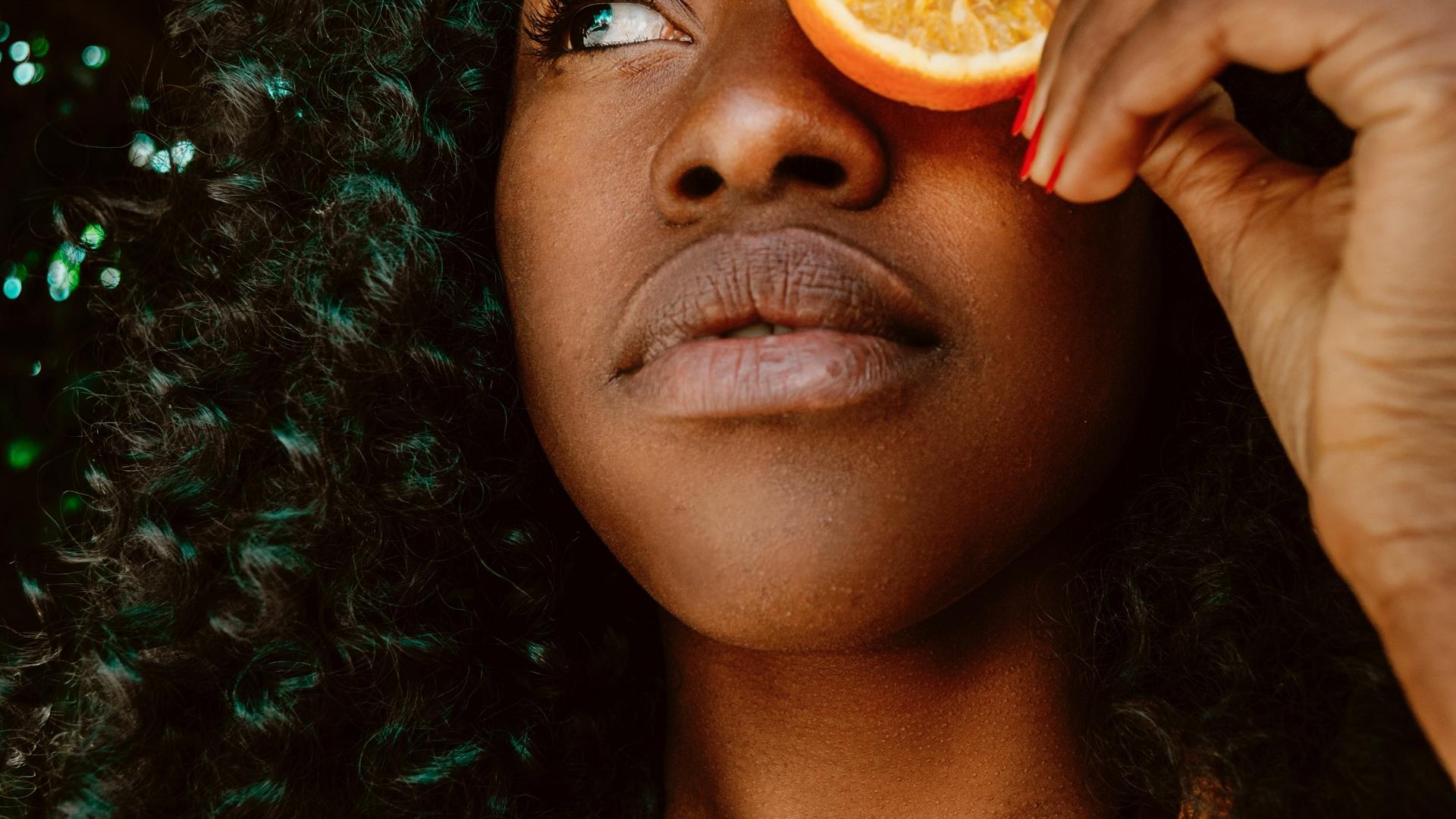 Frau mit schönen Haaren und einer Orange
