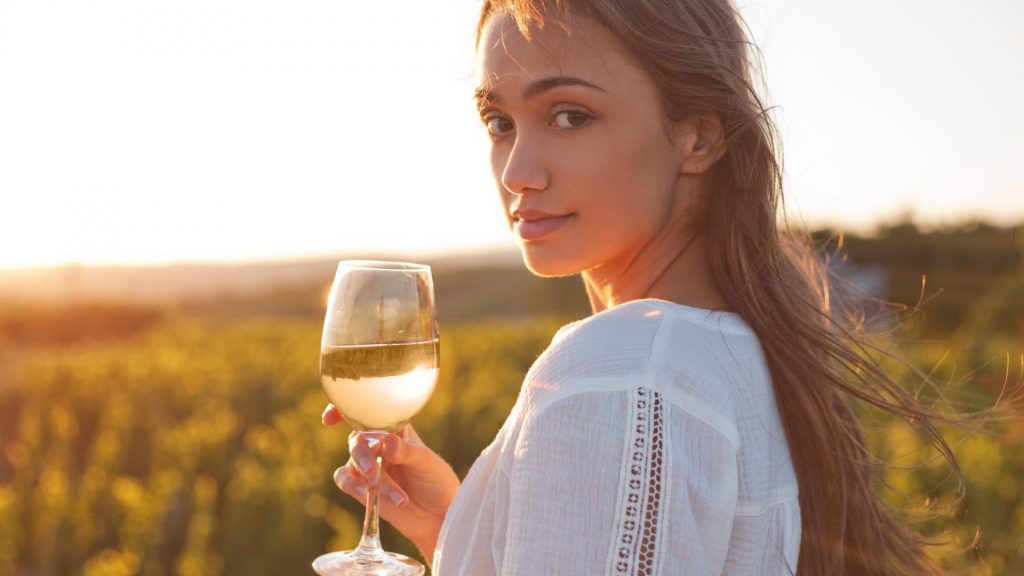 Weißwein Frau auf dem Feld mit Weißwein in der Hand.