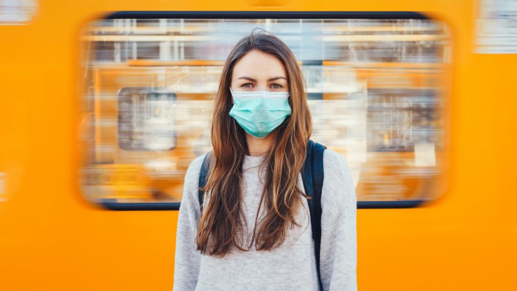 Frau mit Corona Maske vor Bahn