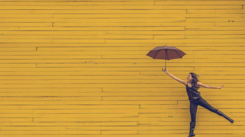 Frau mit Regenschirm vor gelben Holzdielen