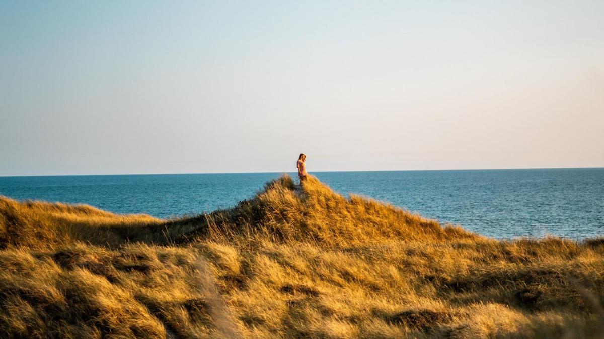 Frau steht auf einer Düne an der Küste