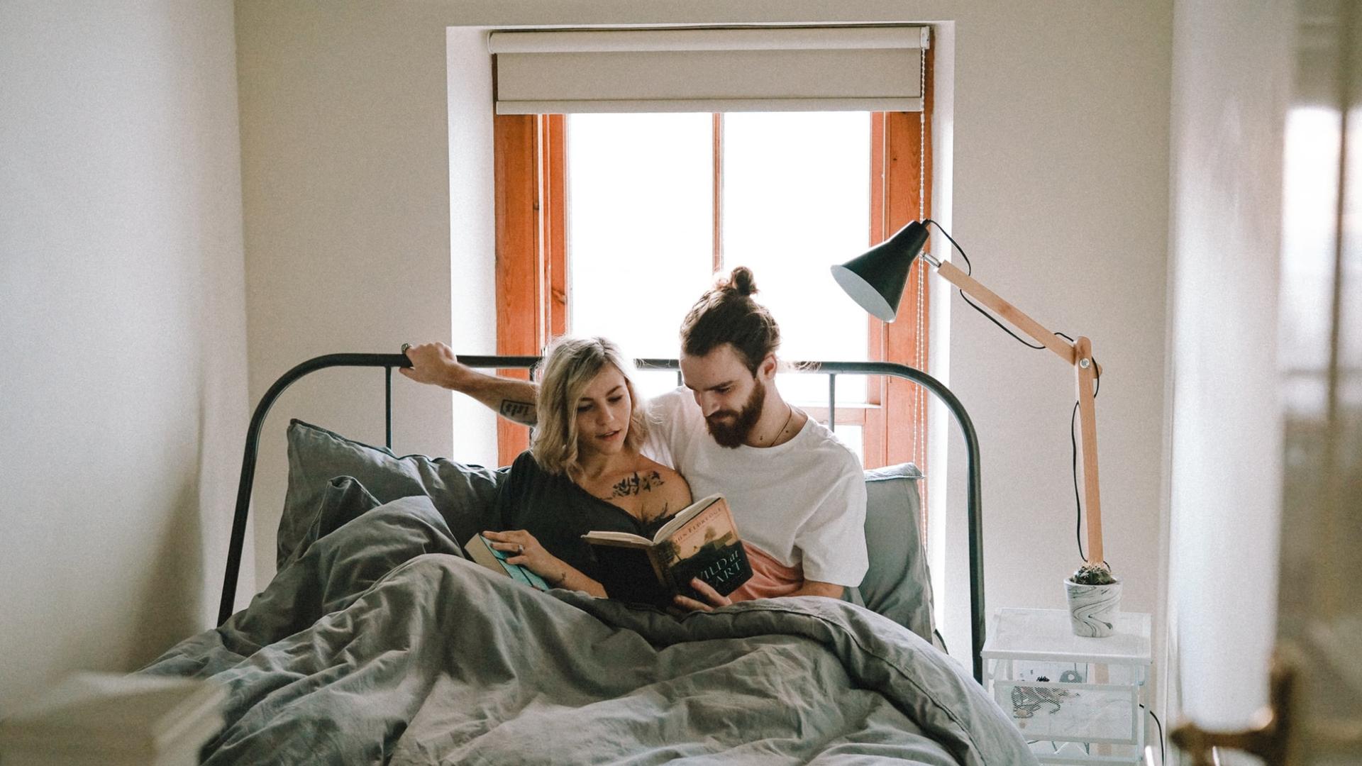 Paar sitzt im Bett und liest ein Buch