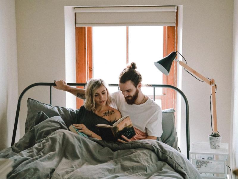Paar sitzt im Bett und liest ein Buch