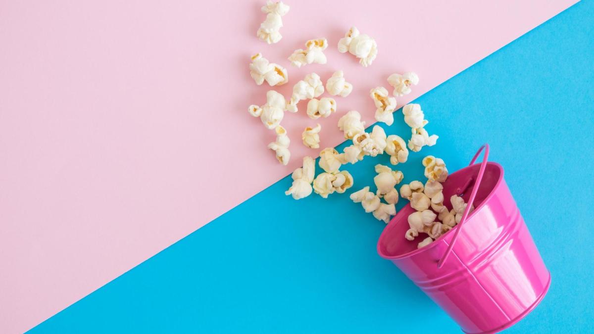 Popcorn in einem rosa Eimer und auf einem rosa-blauen Hintergrund