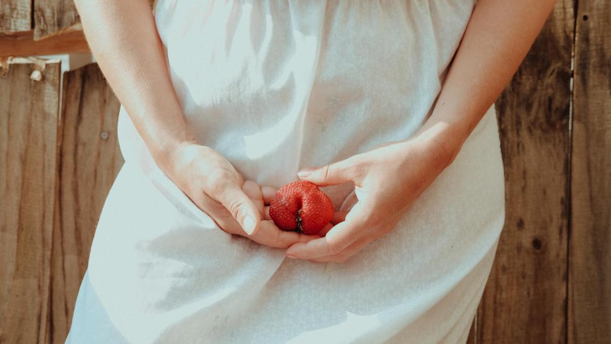 Vulva Watching: Frau hält eine Erdbeere vor ihr Becken