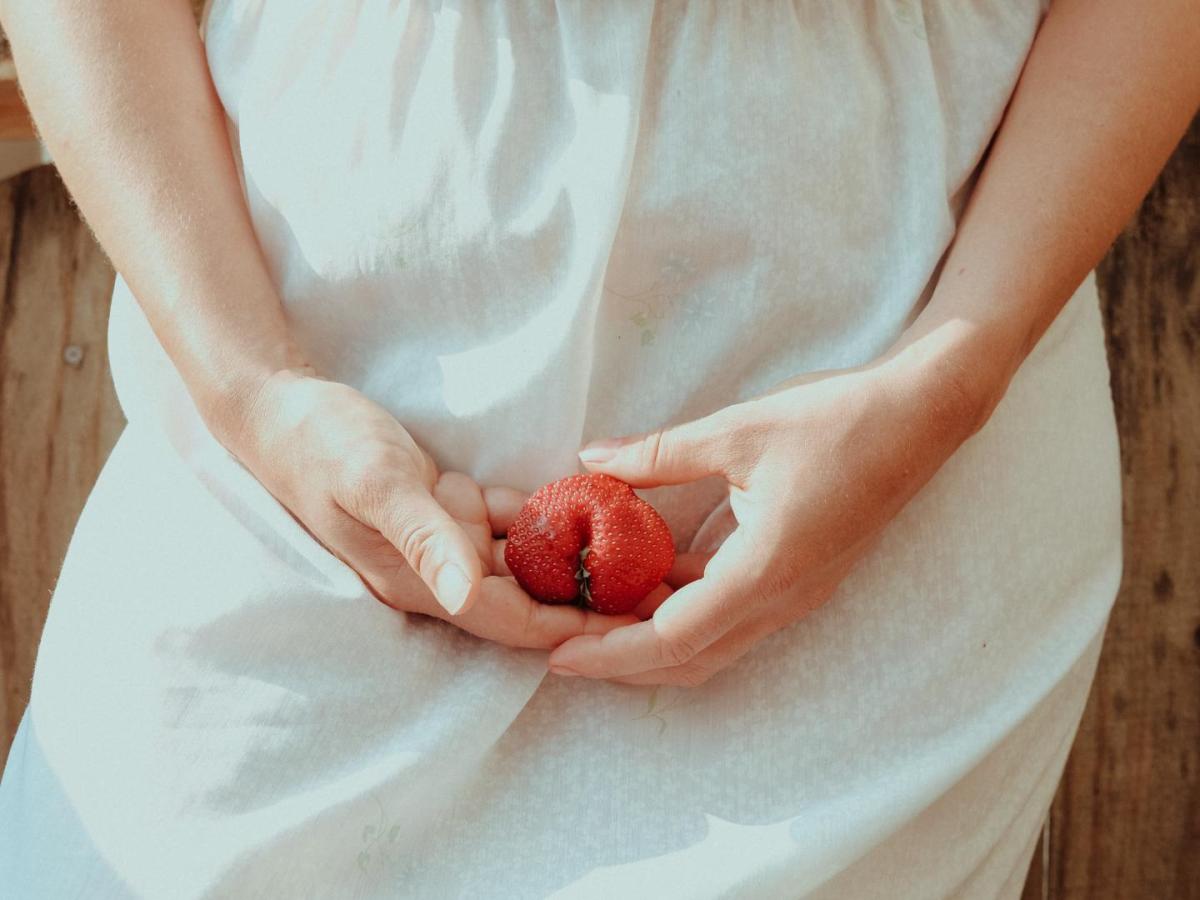 Vulva Watching: Frau hält eine Erdbeere vor ihr Becken