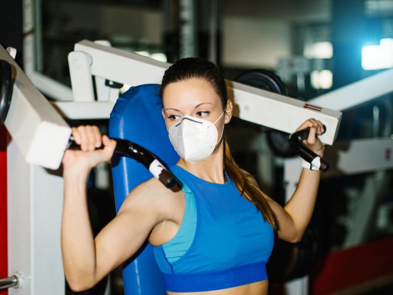 frau gym maske mundschutz gewichte sport fitness muskeln