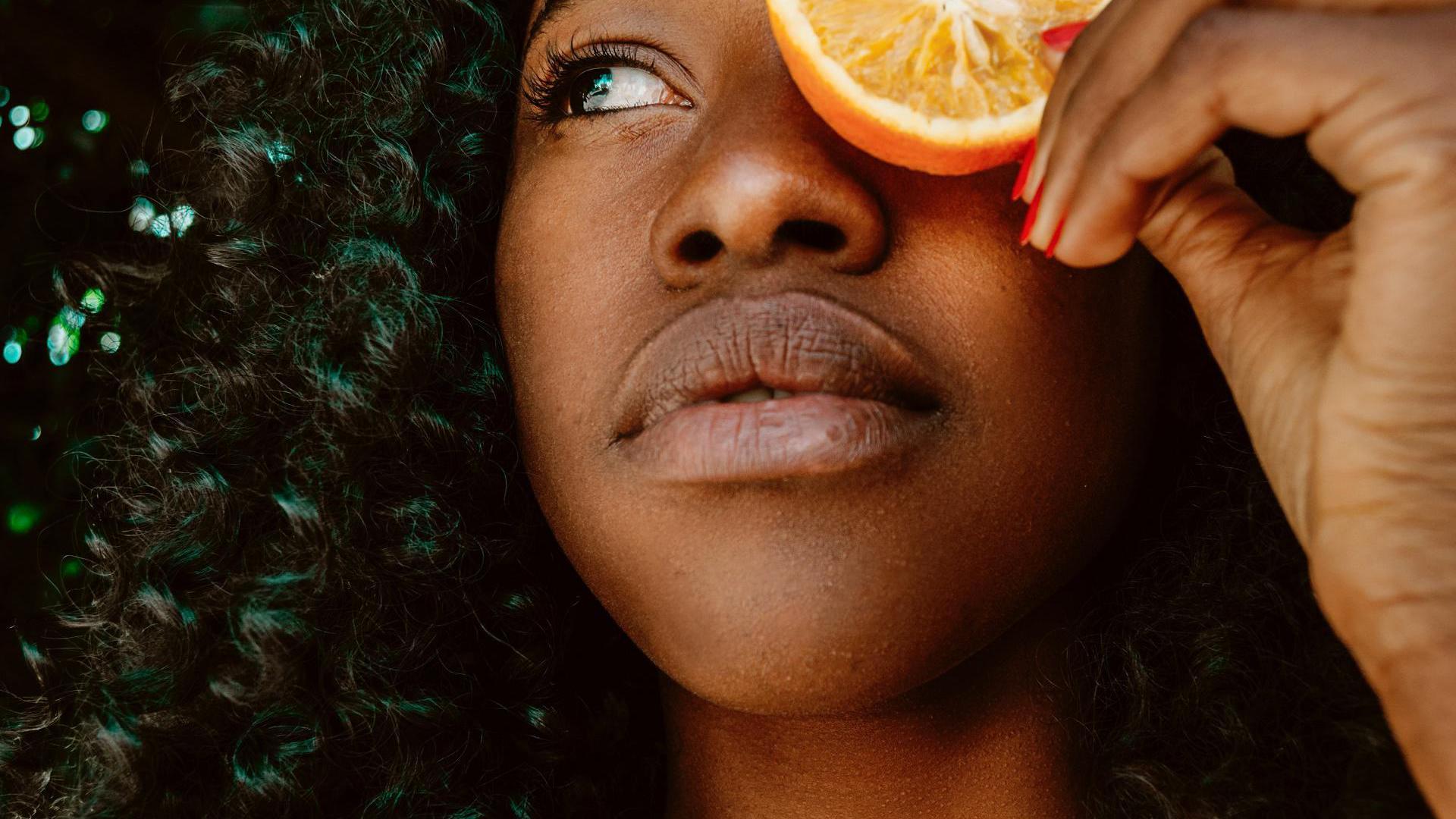 Frau mit schönen Haaren und einer Orange