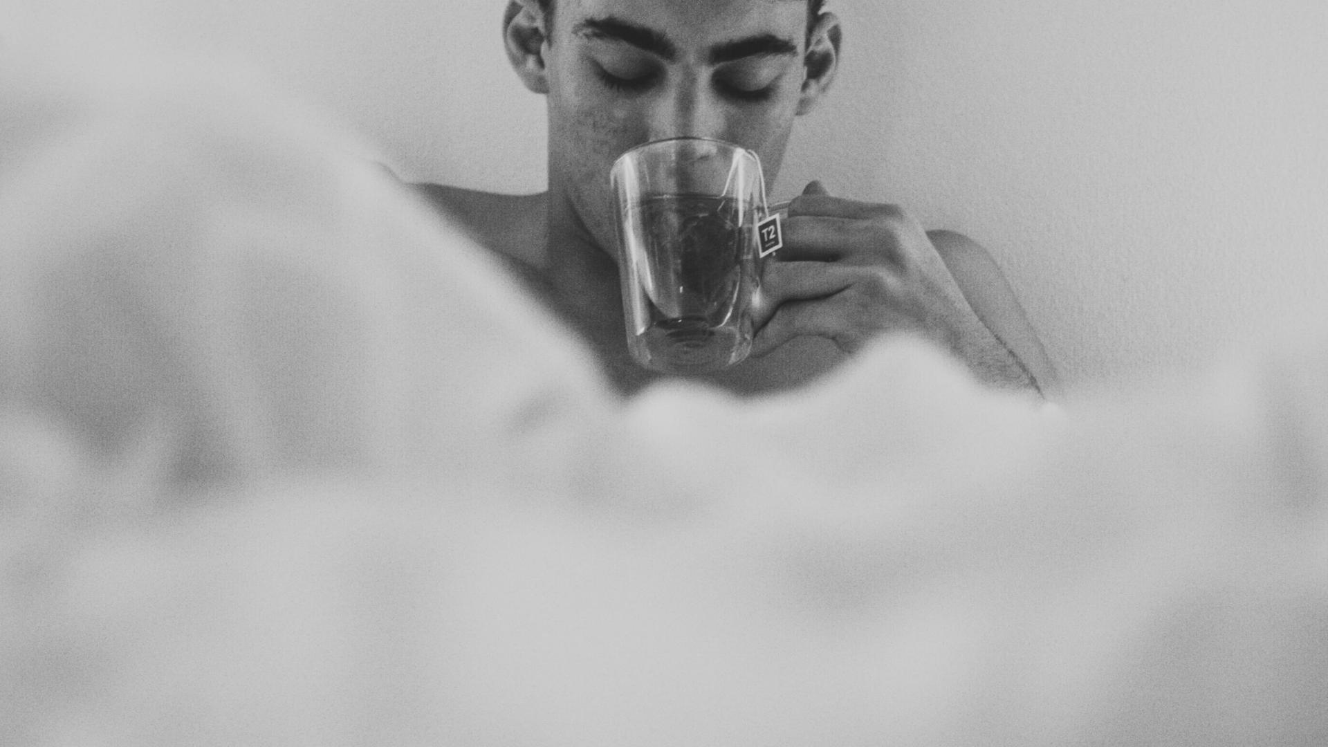 Mann im Bett trinkt Kaffee