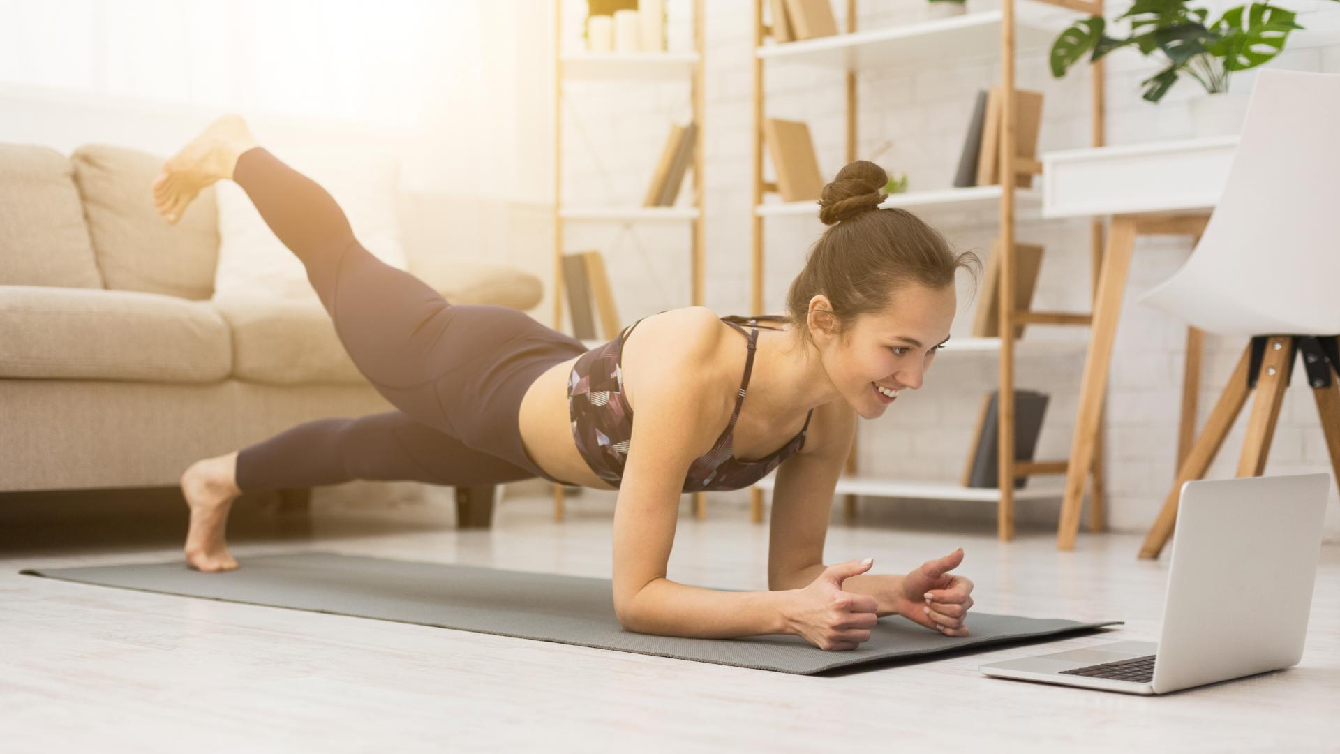 Junge Frau trainiert zuhause vor Laptop