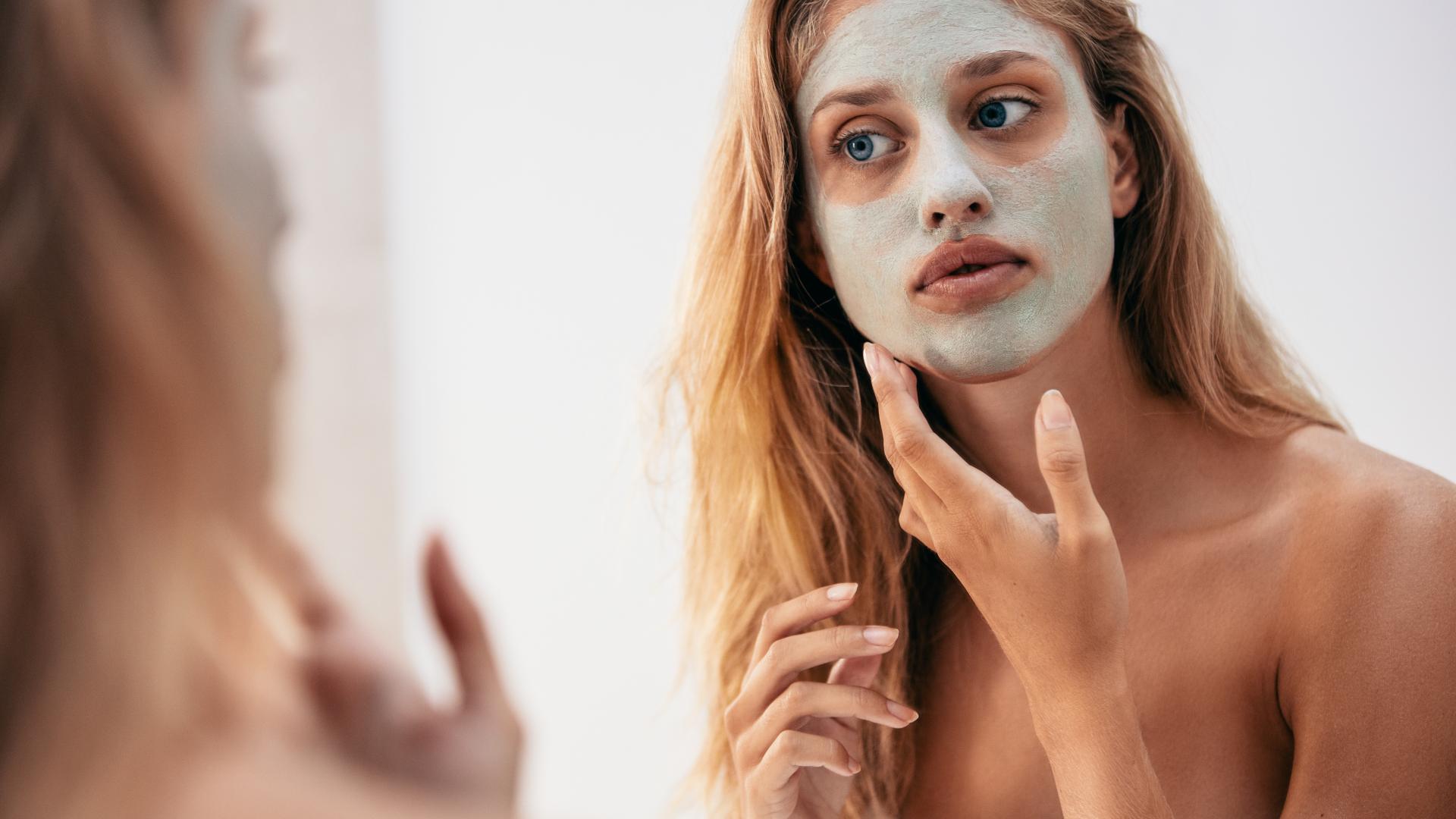 Frau vor dem Spiegel mit Gesichtsmaske