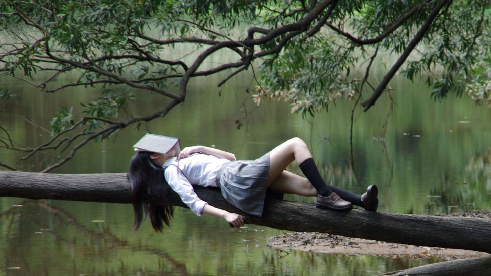 Frau schläft mit Buch auf Kopf