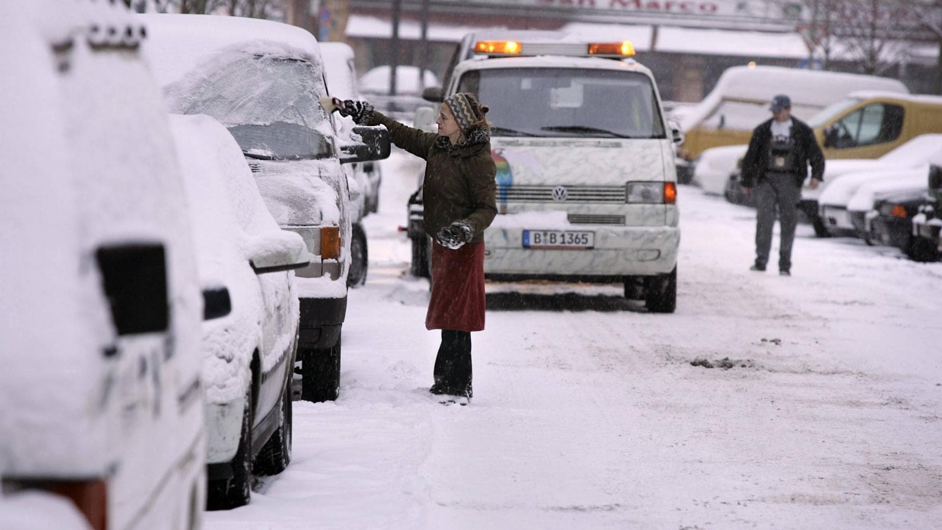 Frau versucht ihr Auto vom Schnee zu befreien nach starken Schneefällen