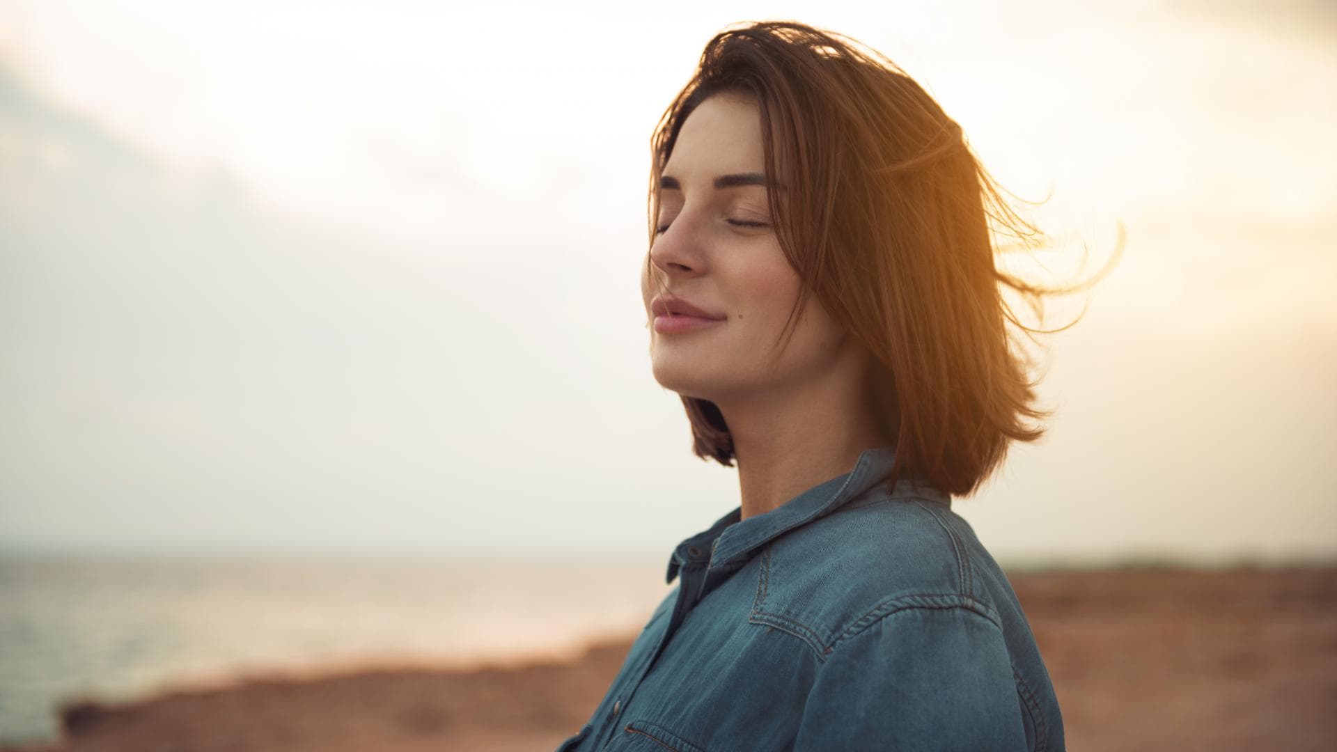 frau genießt sonne am strand kurze braune haare