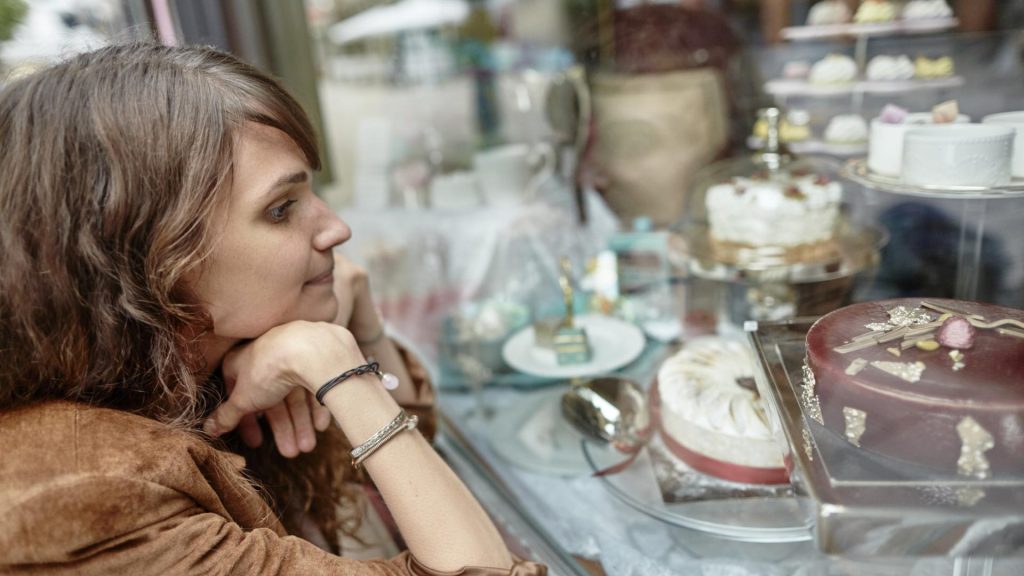 frau schaufenster torten sehnsüchtiger blick ernährung umstellen