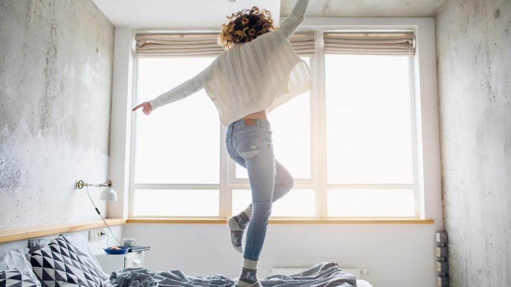 po form frau tanz in jeans happy auf dem bett