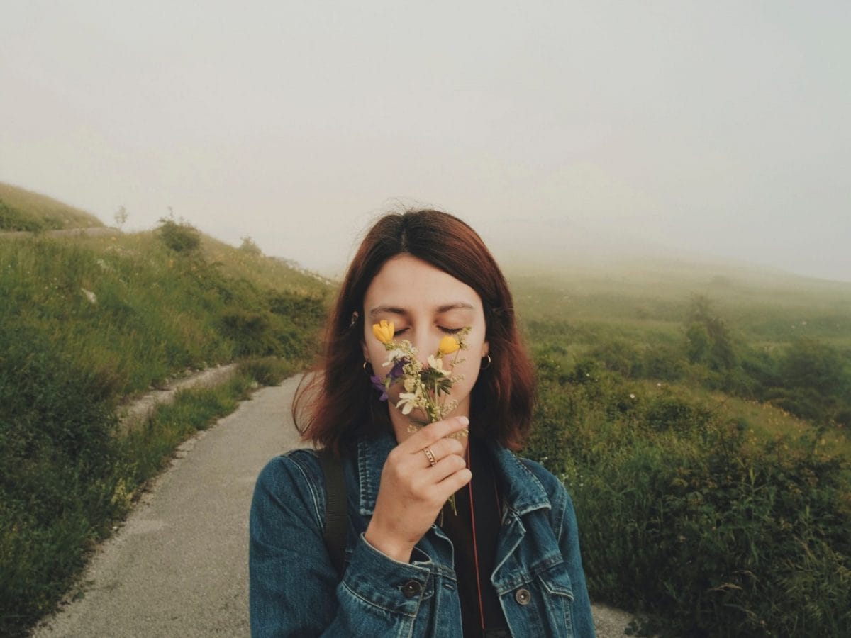 gut riechen frau auf dem feld riecht an einer blume fröhlich