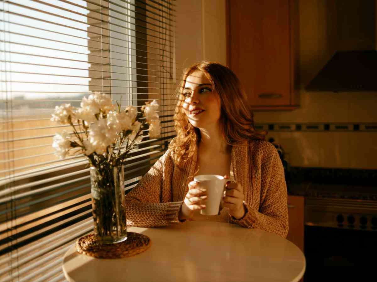 Frau am Tisch mit Kaffee in der Hand