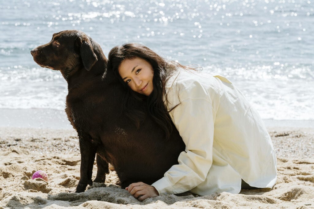 Frau mit Hund am Strand. Verreisen mit Hund