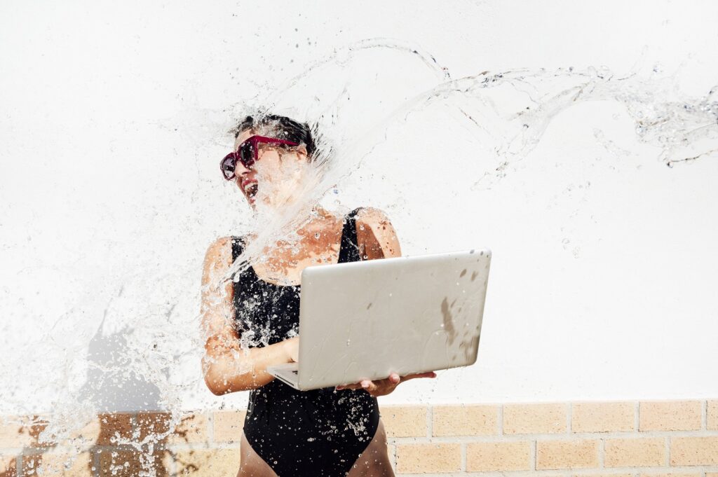 Frau mit Laptop in der Hand wird nass gespritzt