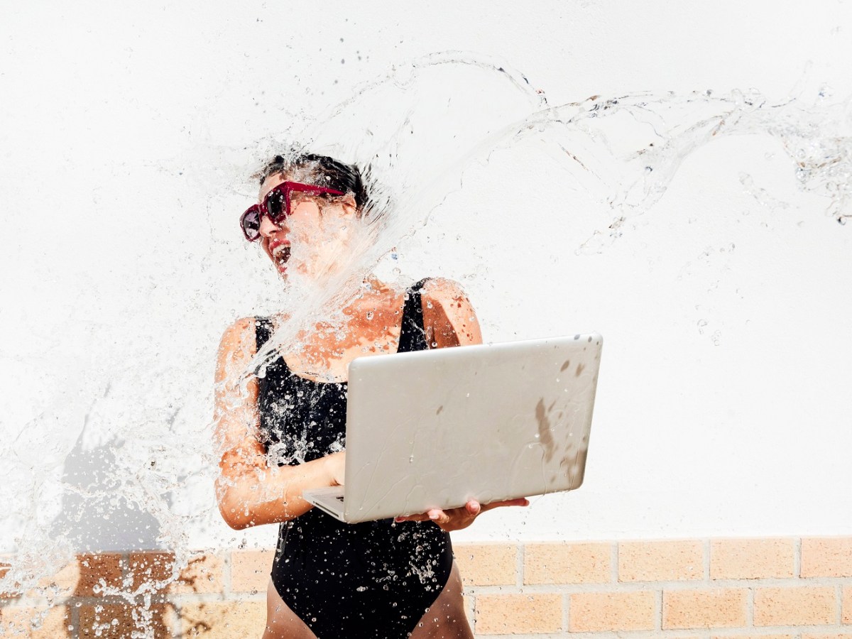 Frau mit Laptop in der Hand wird nass gespritzt