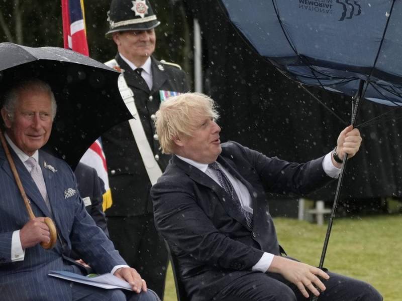 Prinz Charles (li.) kann sich ein Lächeln über Boris Johnsons Schirm-Problem nicht verkneifen.. © imago/i Images