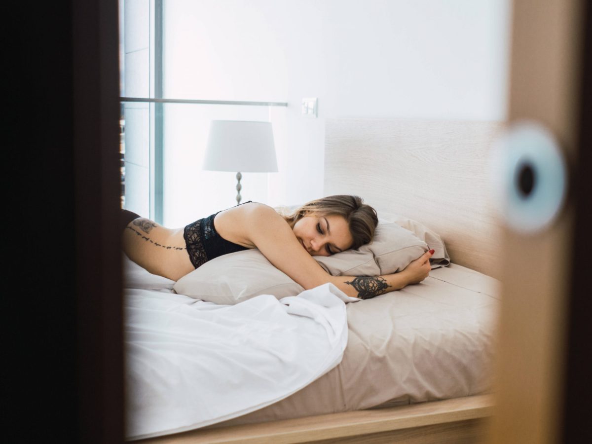 Frau im Bett bei offener Schlafzimmertür