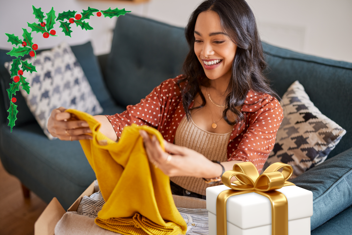 Eine Frau packt ein gelbes Kleidungsstück aus einem Paket aus. Daneben steht ein Geschenk.