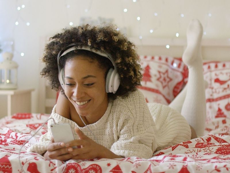 Frau liegt auf Bett und hört Musik