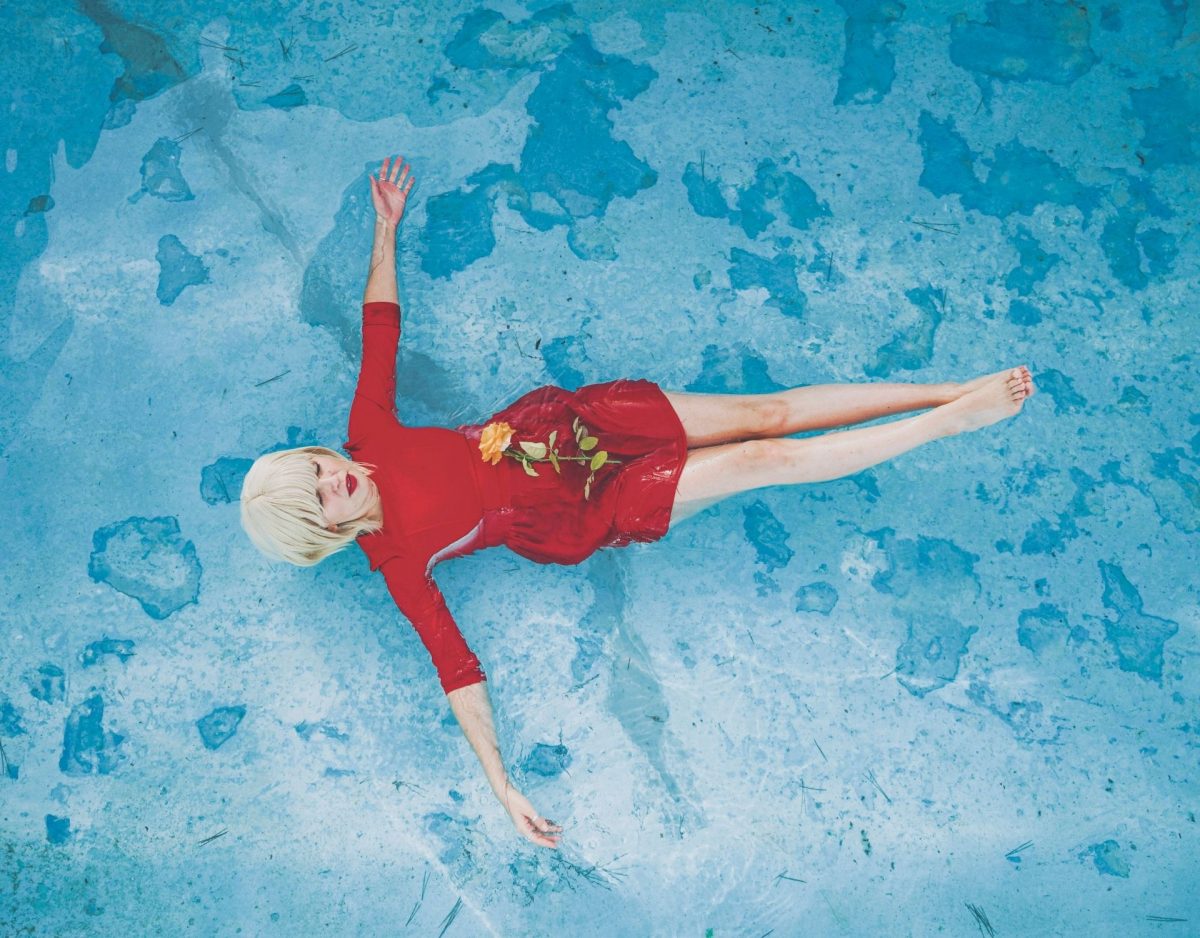 Frau mit rotem Kleid schwimmt im Pool
