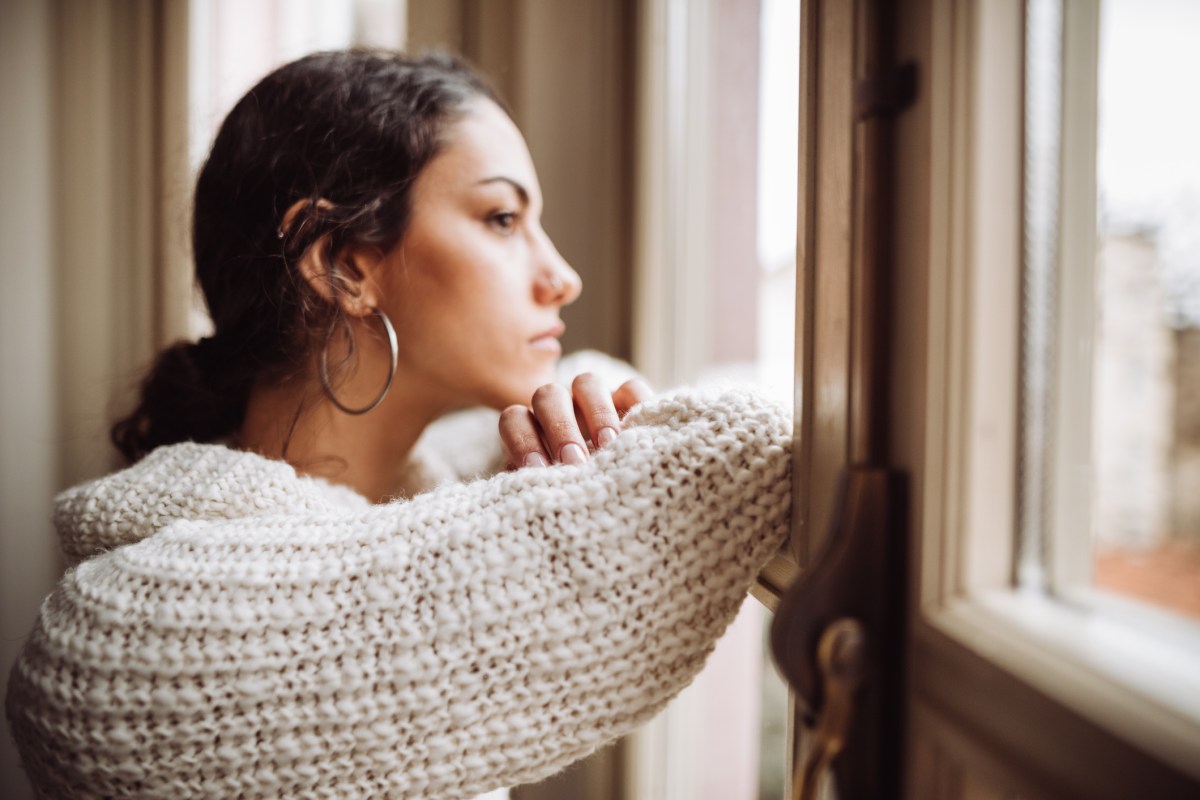Weltschmerz Frau guckt traurig und nachdenklich aus dem Fenster