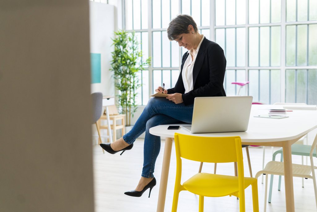 Frau schreibt auf einem Tisch sitzend