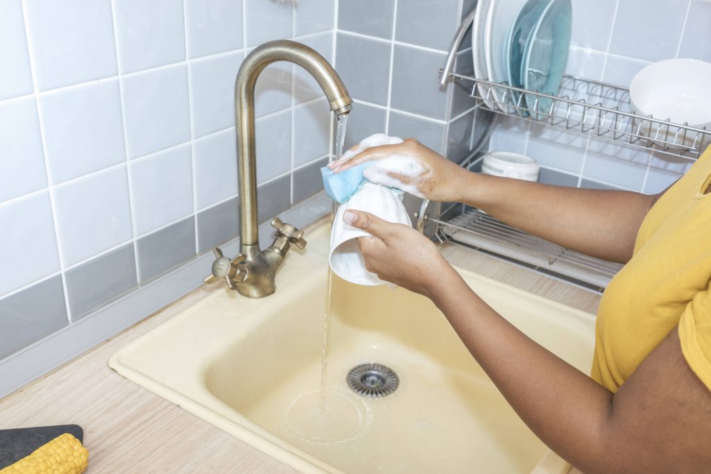 Frau wäscht Geschirr Wasser sparen