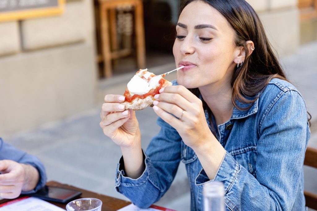 Frau isst Pizza mit viel Käse