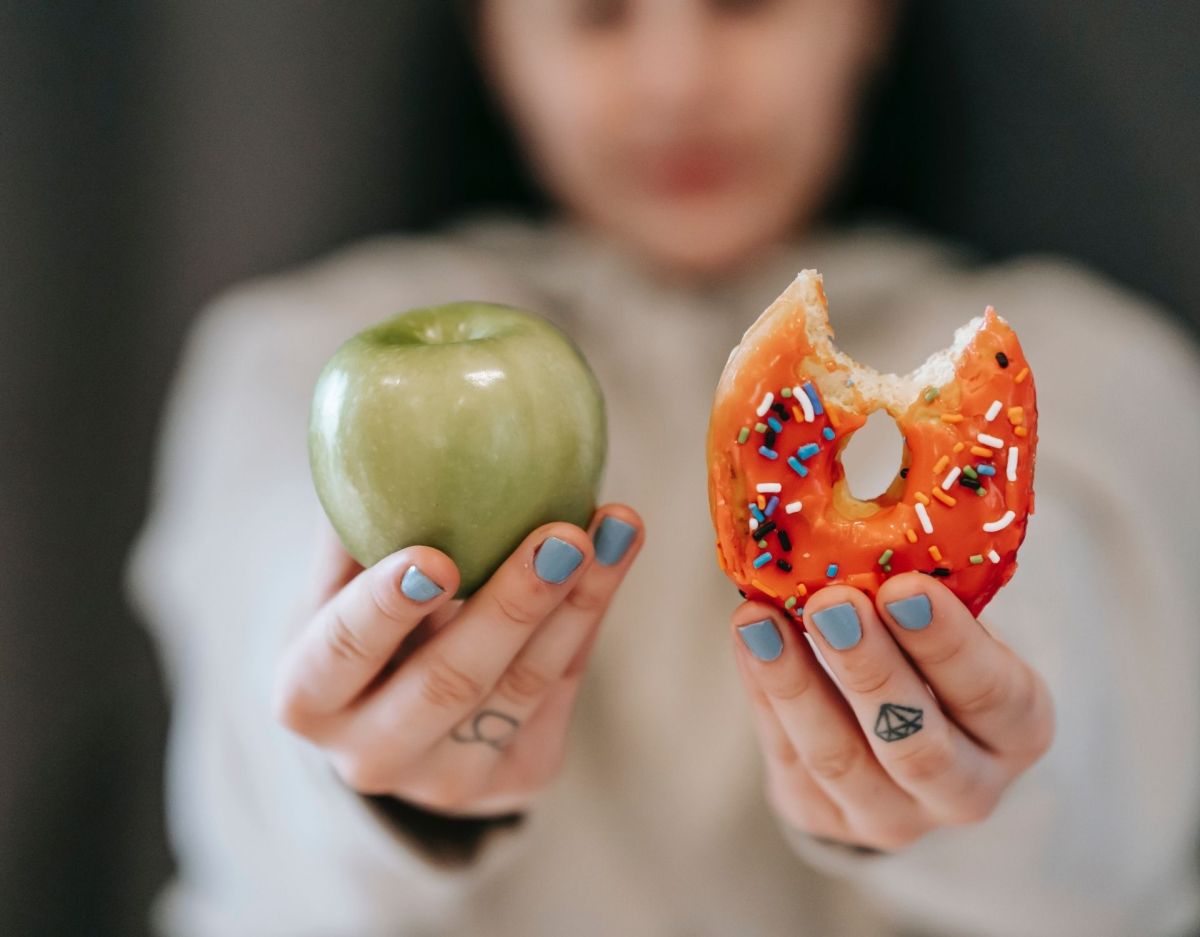 Frau hält Apfel und Donut hoch