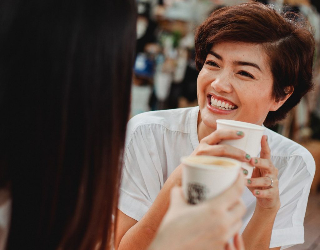 Frau lächelt mit Kaffeetasse in der Hand