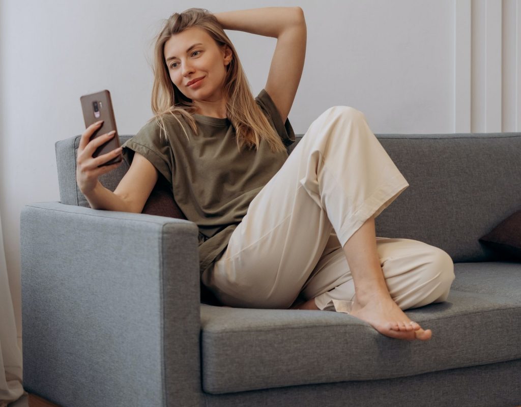 Frau auf Sofa macht Selfie