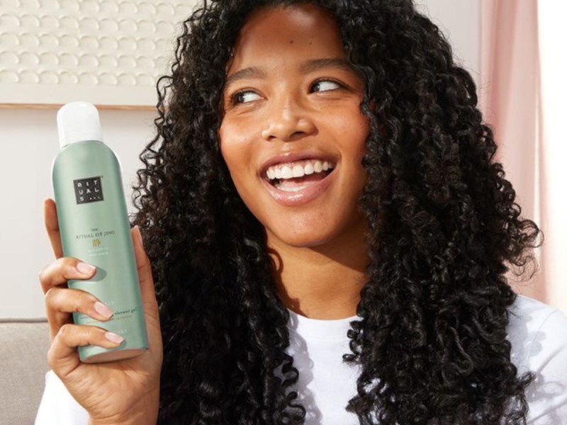Junge Frau hat GLOSSYBOX abonniert und freut sich über ein RITUALS Duschgel.