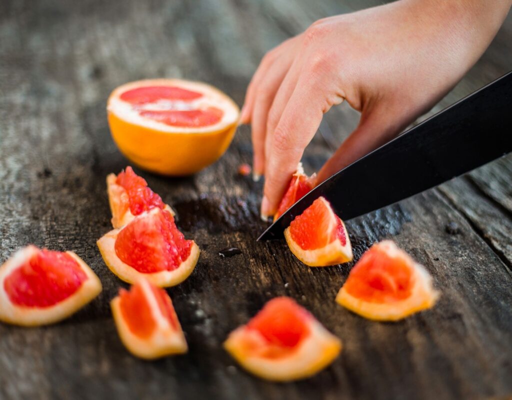 Hand schneidet Grapefruit gesund