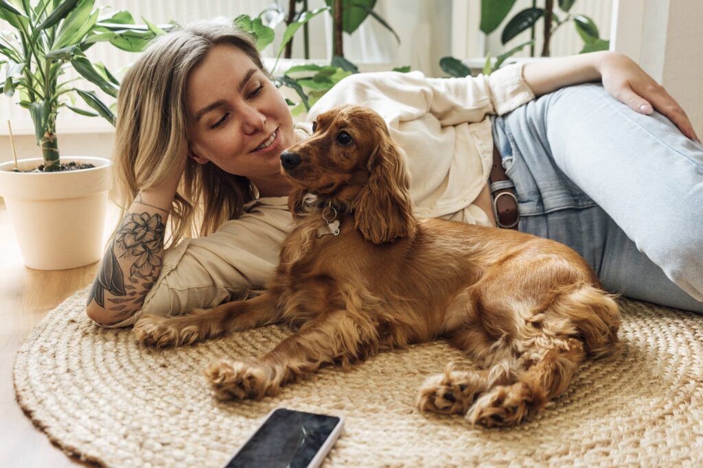 Frau liegt mit Hund auf dem Boden