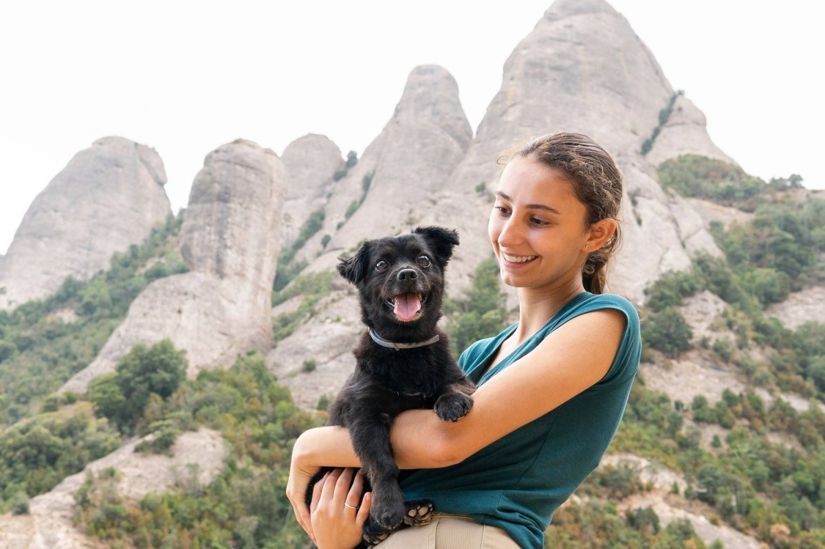 Lachende Frau mit Hund auf dem Arm