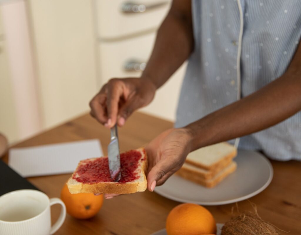 Frau bestreicht Brot mit Marmelade