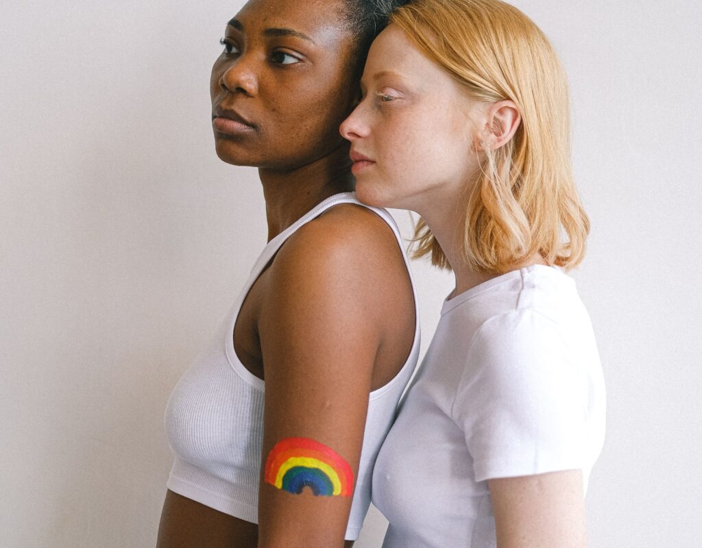 Zwei Frauen im Portrait, eine hat einen Regenbogen auf den Arm gemalt