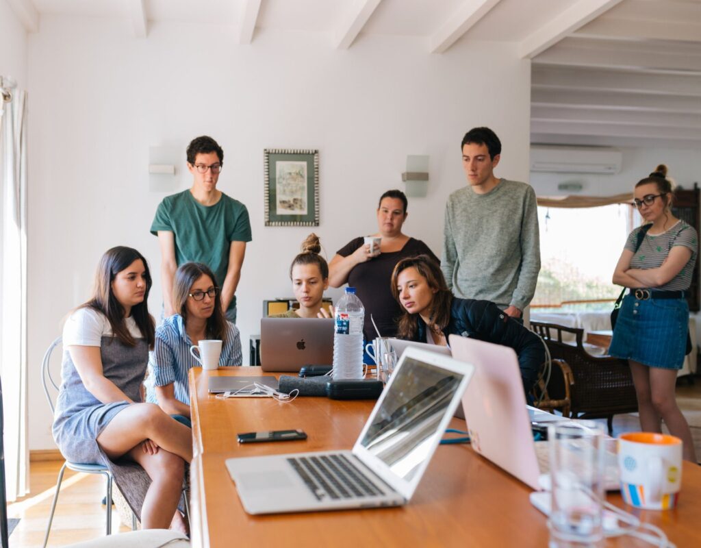 Arbeitsmeeting, Menschen stehen um einen Laptop herum