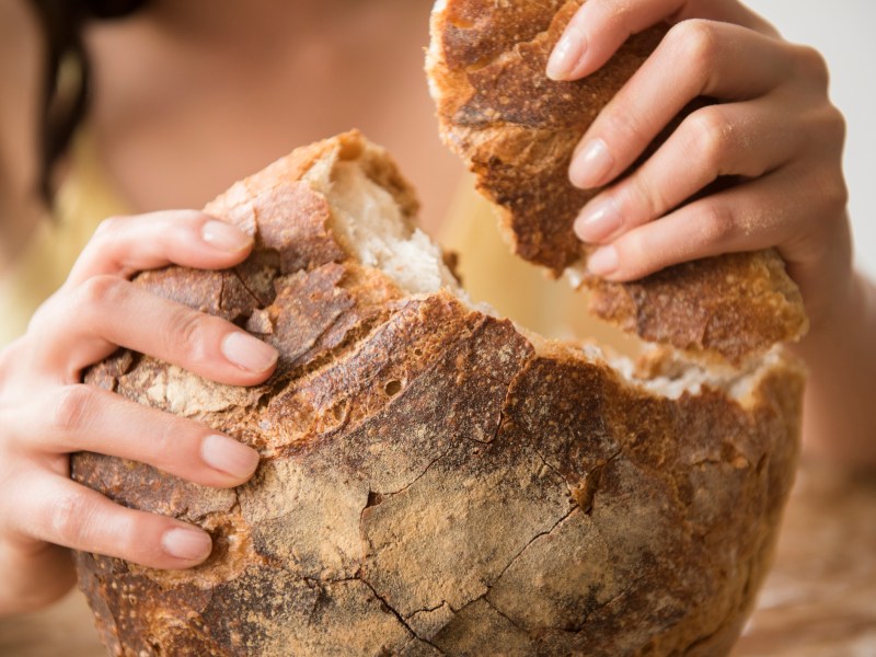 Frau reißt Stück von Brot ab
