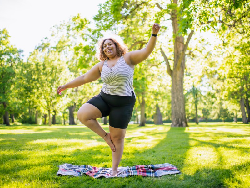 Frau im Park steht auf einem Bein