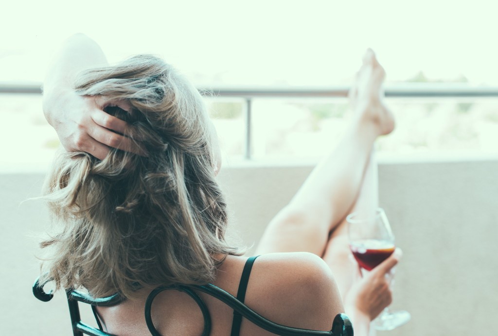 Alkohol Sport: Frau trinkt Rotwein auf Balkon